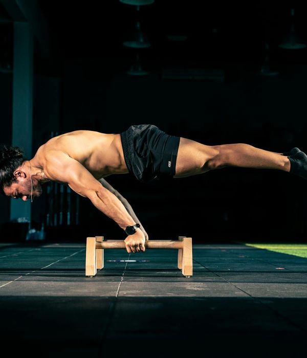 Man performing a controlled strength exercise in a minimalist dark gym.